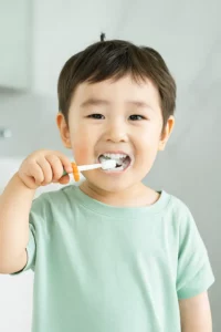 A 4-year-old child is happily brushing their teeth with a toothbrush